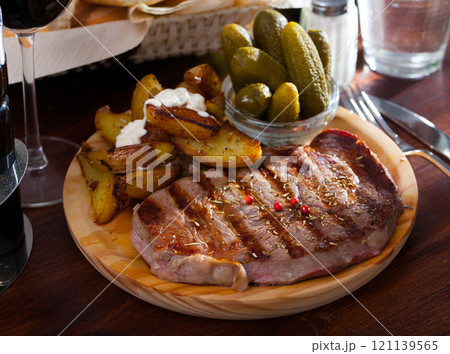 Appetizing beef entrecote with boiled potatoes and pickled cucumbers 121139565