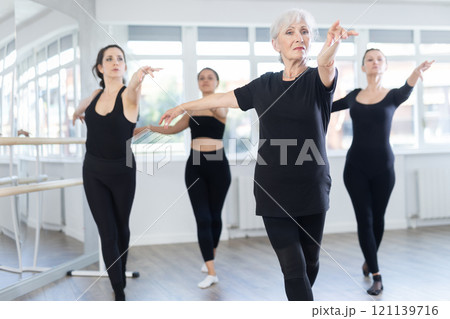 Graceful women of different ages practice various ballet movements in choreographic studio 121139716