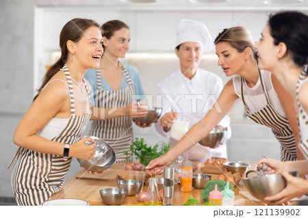 Young woman learning to cook and chatting at master class Young woman learning to cook and chatting at master class 121139902