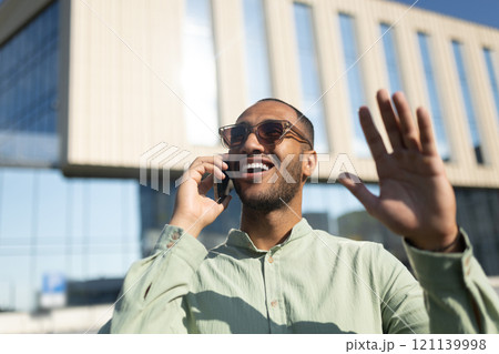 Black man walking on city street and talking on mobile phone 121139998