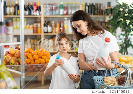 Checking expiration date of milk - mother and daughter checking qr code on bottle of milk 121140051