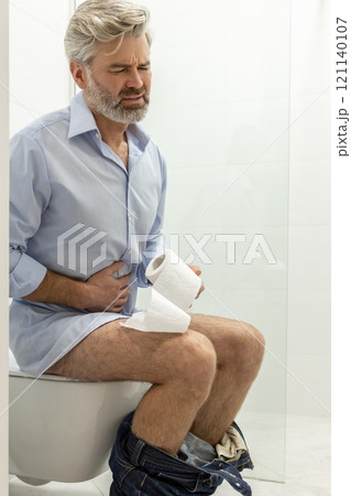 Man sitting in a toilet and having problems with digestion 121140107