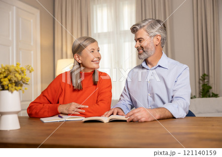 Mature couple sitting at the table and making notes together 121140159