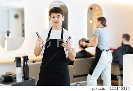 Guy hairdresser stylist stands near workplace with tool in hands. 121140316