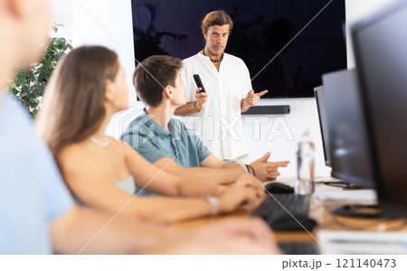 Instructor conducting software development courses to young guys and girls 121140473