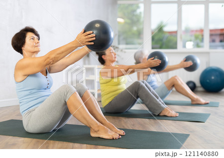 Group of elderly woman doing pilates with soft ball in studio 121140880