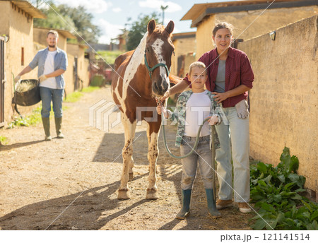 Woman and boy lead horse to feed Woman and boy lead horse to feed 121141514