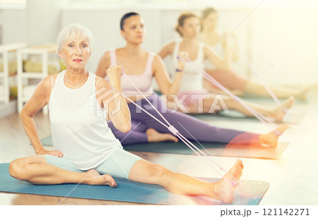 Elderly woman exercising with pilates loop 121142271