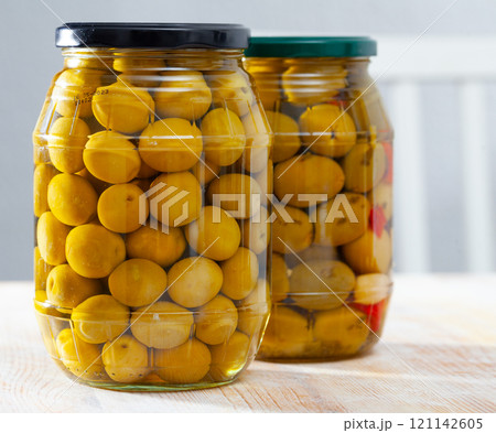 Glass jar with delicious whole olives at wooden table 121142605