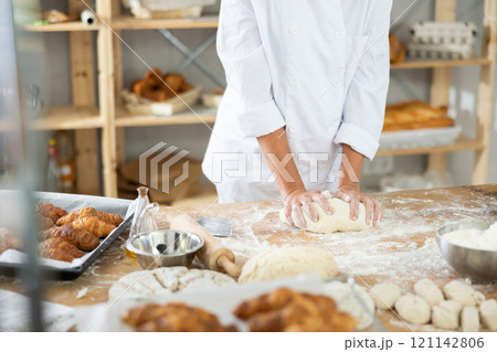 Female hands kneading dough on table, closeup 121142806