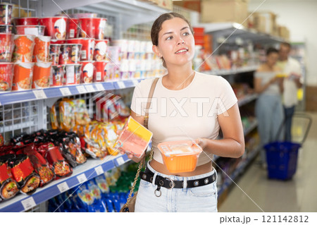 Young woman choosing instant noodles in store 121142812