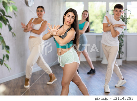 Ordinary teen girls and boy performing kick step movement during training together in dance studio Ordinary teen girls and boy performing kick step movement during training together in dance studio 121143283