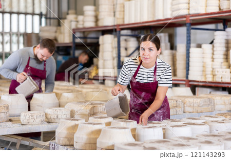Female ceramicist filling casting molds with slip in pottery workshop 121143293