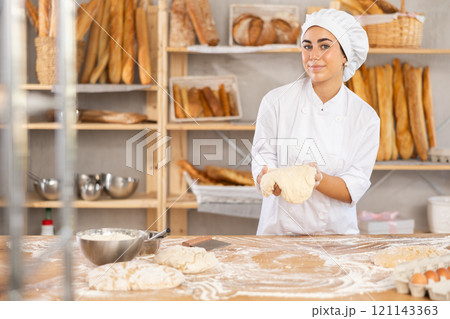 Young woman baker kneads the dough in bakery Young woman baker kneads the dough in bakery 121143363