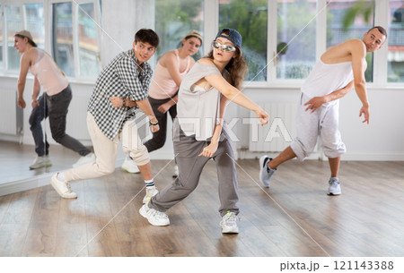 Young girl standing performs basic hip hop movements in front of group of students Young girl standing performs basic hip hop movements in front of group of students 121143388