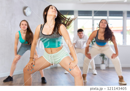 Expressive Hispanic teenage girl dancing hip-hop with group in studio Expressive Hispanic teenage girl dancing hip-hop with group in studio 121143405