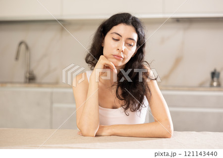 Young upset woman sitting at table in kitchen 121143440