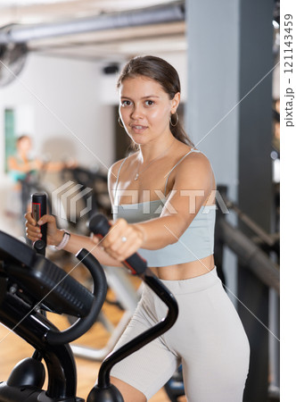 Sporty girl working out on elliptical machine in gym. Healthy active lifestyle concept Sporty girl working out on elliptical machine in gym. Healthy active lifestyle concept 121143459