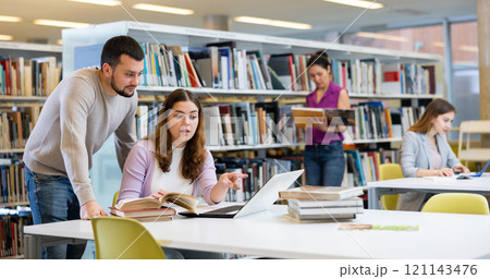 Woman and man studying together at library Woman and man studying together at library 121143476