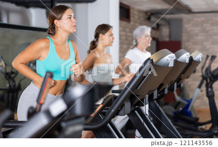 Focused motivated girl leading healthy active lifestyle doing cardio workout in gym, running on treadmill 121143556