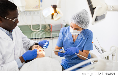 Orthodontist and chairside assistant working on dental restoration for woman 121143854