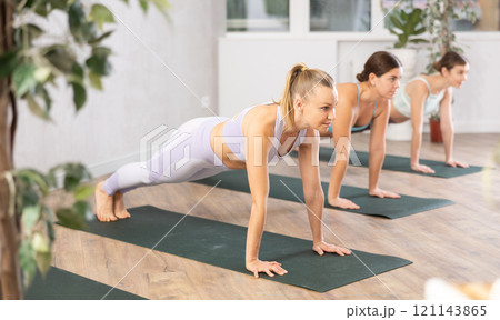 Active women perform the exercise while standing in the plank position 121143865
