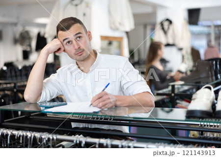 Young man signing document in clothing store Young man signing document in clothing store 121143913