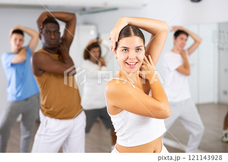 Group of active women and men practicing energetic dance in modern dance studio 121143928