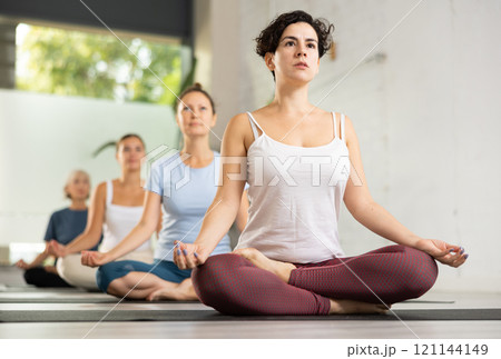 Portrait of latin american woman making yoga meditation in lotus pose in fitness studio Portrait of latin american woman making yoga meditation in lotus pose in fitness studio 121144149