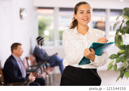 Happy young woman standing with her back to waiting room 121144150