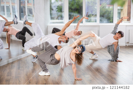 Girl and her students perform hip hop dance on one bent leg, movement in horizontal plane near floor Girl and her students perform hip hop dance on one bent leg, movement in horizontal plane near floor 121144182