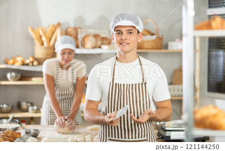 Young male baker holding a dough cutter in bakery Young male baker holding a dough cutter in bakery 121144250