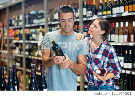 Married couple chooses wine in the alcohol department of supermarket 121144501