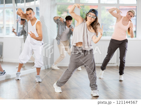 Young girl standing performs basic hip hop movements in front of group of students Young girl standing performs basic hip hop movements in front of group of students 121144567
