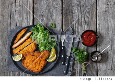 Pork Milanese with lettuce and lemon on a plate 121145323