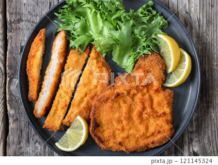 Pork Milanese with lettuce and lemon on a plate 121145324