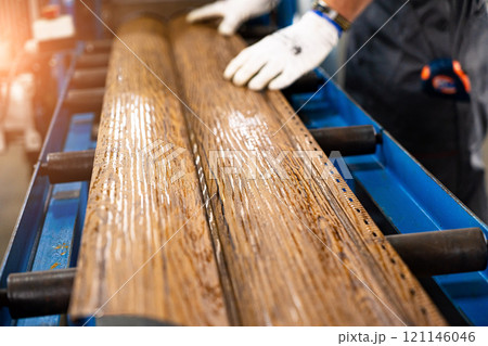 A factory worker is making a metal profile for a roof. Worker at factory measures metal profiled sheet. He works in metal production industrial. metal roofing production, production of roof elements A factory worker is making a metal profile for a roof. Worker at factory measures metal profiled sheet. He works in metal production industrial. metal roofing production, production of roof elements 121146046