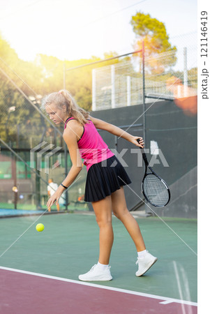European woman serving ball while playing tennis during training European woman serving ball while playing tennis during training 121146419