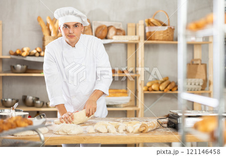 Young male baker kneading dough in bakery Young male baker kneading dough in bakery 121146458