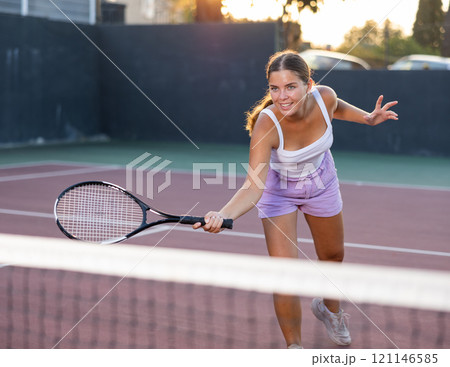 Young woman in shorts playing tennis on court Young woman in shorts playing tennis on court 121146585