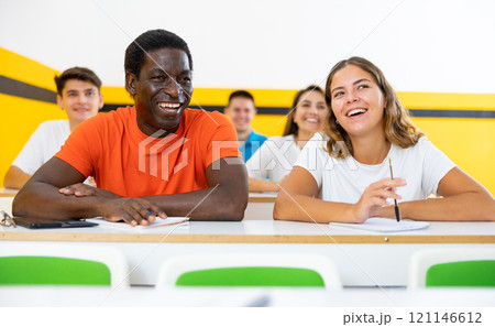 Cheerful smiling adult students at their desks in university classroom Cheerful smiling adult students at their desks in university classroom 121146612