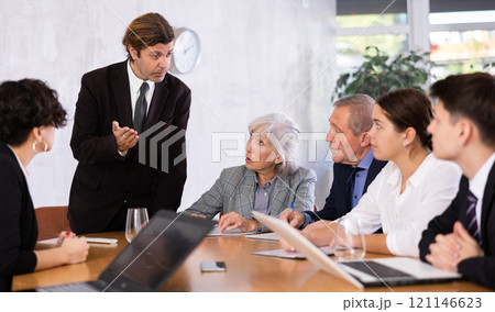 Male director gives instructions to managers in deliberation room 121146623