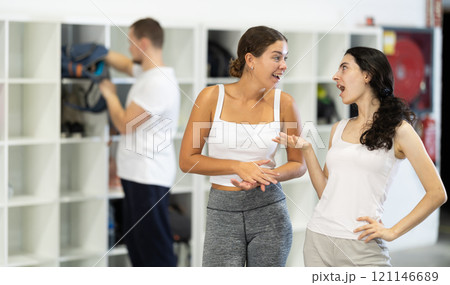 Two female climbers laughing and sharing stories in climbing gym locker room after exciting successful workout 121146689