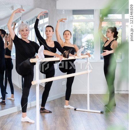 Students of dance studio perform exercises under supervision of middle-aged female coach. 121146809
