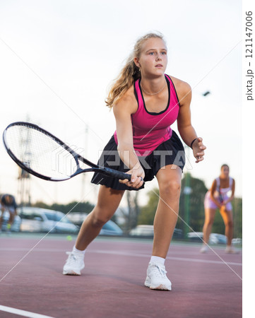 Young forcefully teenage girl playing tennis close to net on court Young forcefully teenage girl playing tennis close to net on court 121147006