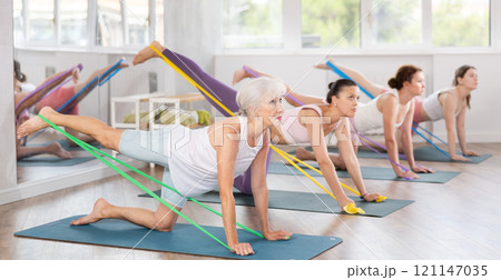 Elderly woman exercises with pilates band 121147035