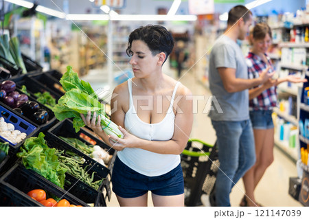 Woman choosing lettuce in supermarket 121147039