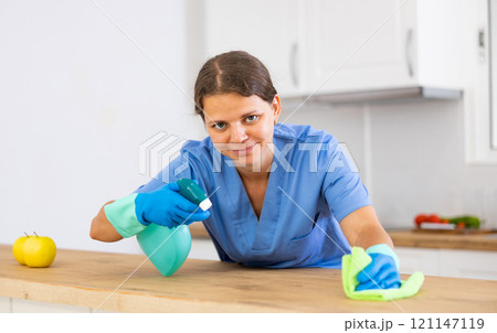 Young woman house cleaner cleaning kitchen countertop 121147119