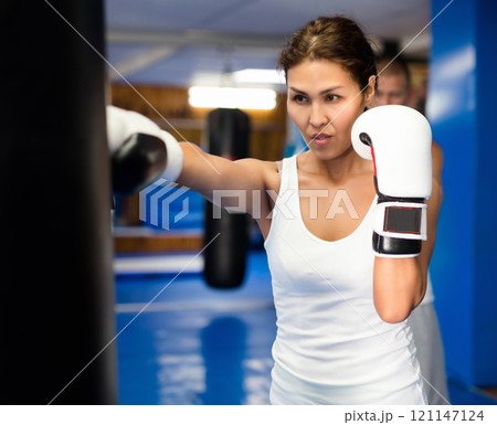 Asian woman training with punchbag Asian woman training with punchbag 121147124