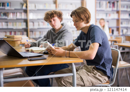 Two teenage friends are reading books and preparing for exams in school library Two teenage friends are reading books and preparing for exams in school library 121147414